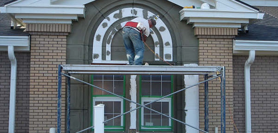 Worker applying stucco to building exterior